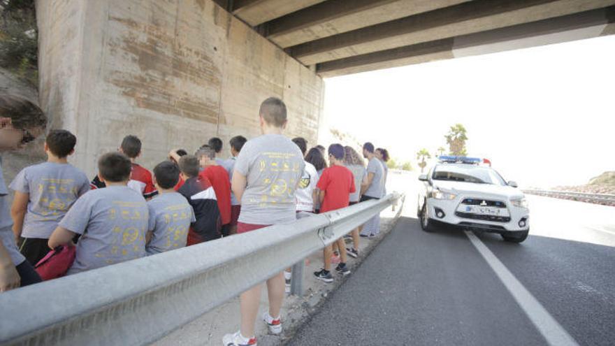 Los niños esperan la llegada del autobús debajo de un puente de la autovía