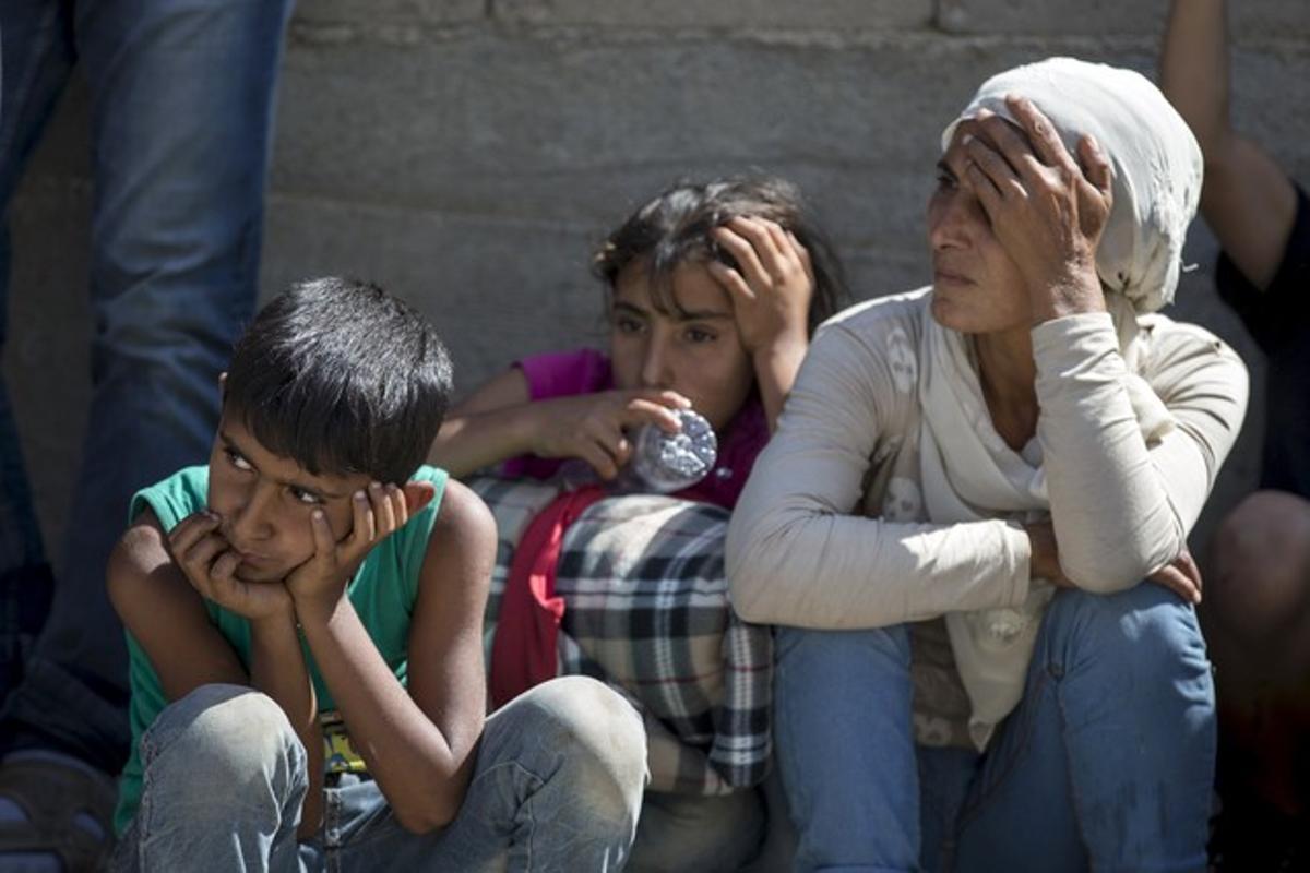 Tres refugiados sirios descansan en el arcen de la carretera de Presevo, en Serbia.