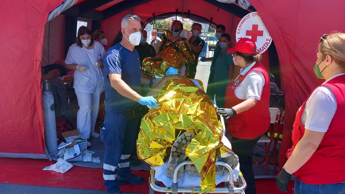 Paramédicos del Servicio Nacional de Ambulancias de Emergencia de Grecia (EKAV) y miembros de la Cruz Roja griega ayudan a migrantes supervivientes del hundimiento de un pesquero en su llegada en el puerto de Kalamata.