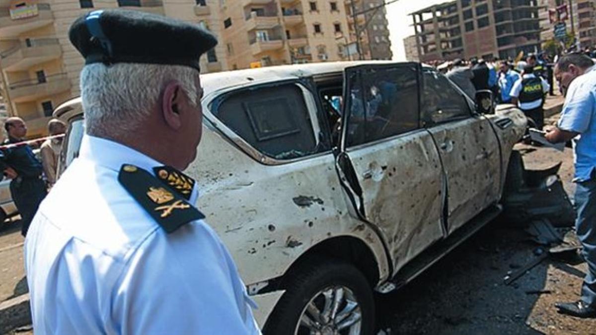 Un agente inspecciona uno de los coches dañados en la explosión.