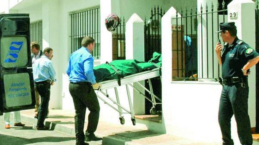 Los operarios de la funeraria sacan el cadáver de la sexagenaria asesinada por su ex pareja.