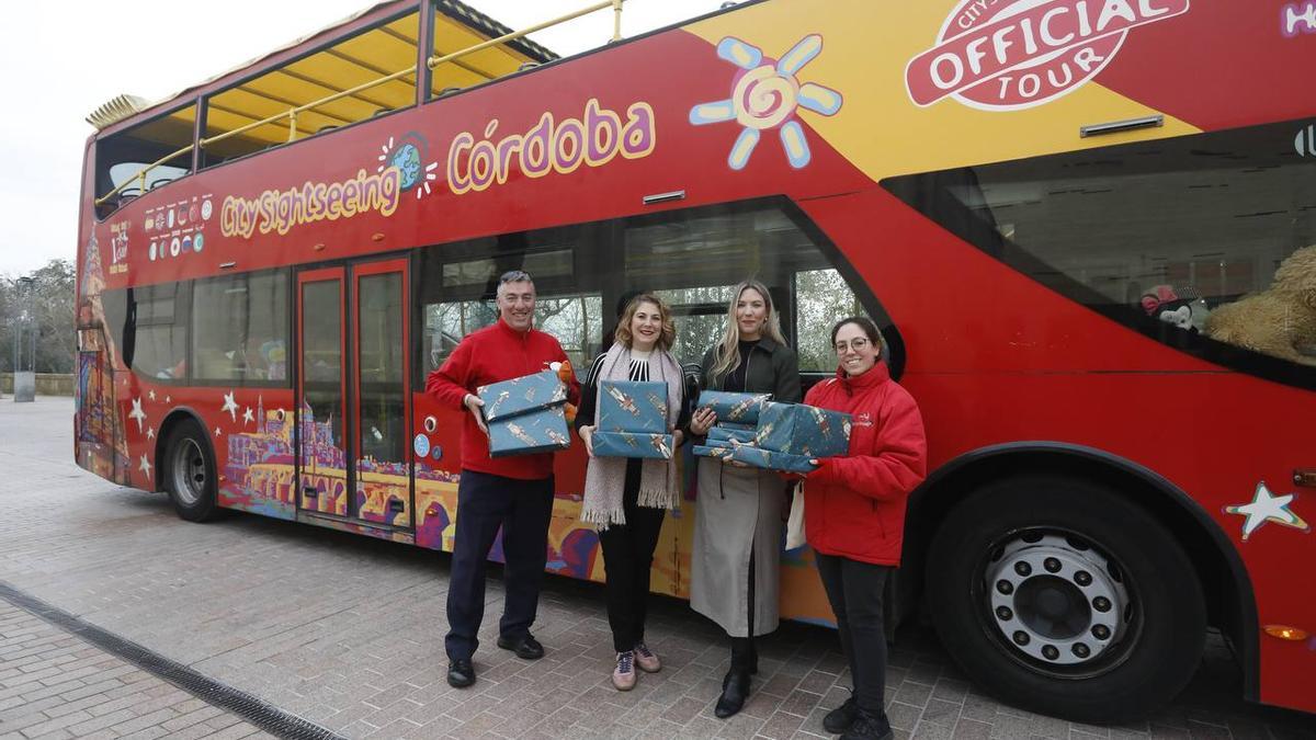 Eva Contador e Inmaculada Guillén junto al autobús turísitco protagonista de la campaña solidaria de juguetes