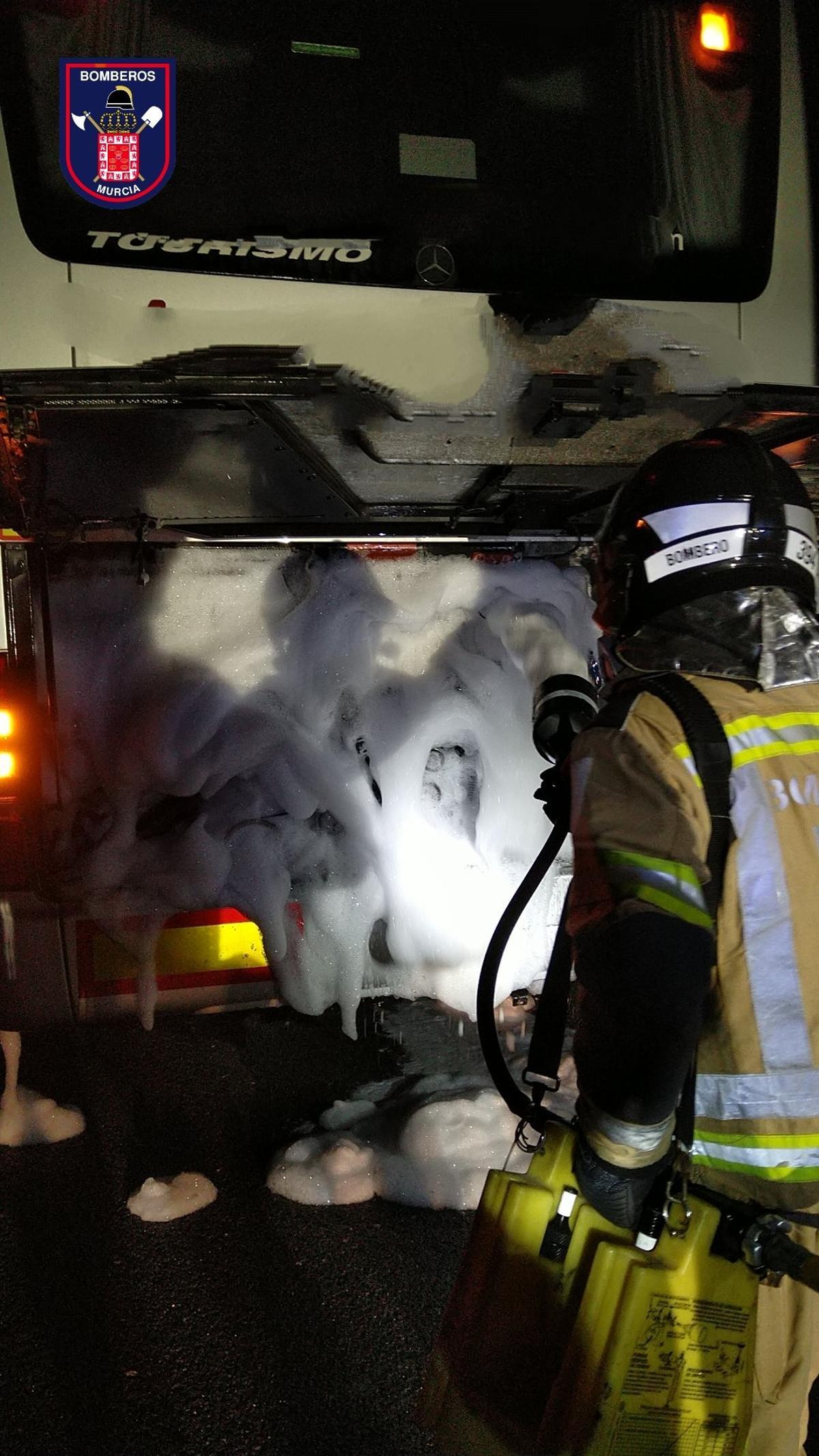 Un bombero echa espuma para apagar el fuego en el motor de un autobús