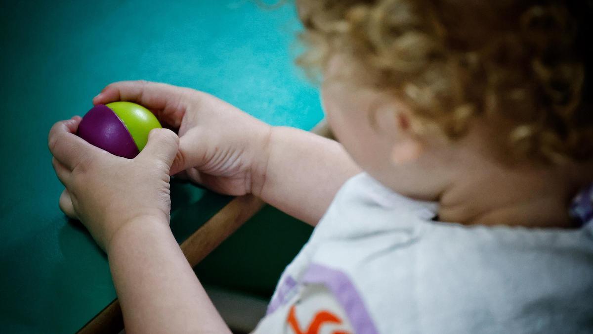 Una niña juega con una pelota en un centro de educación infantil.