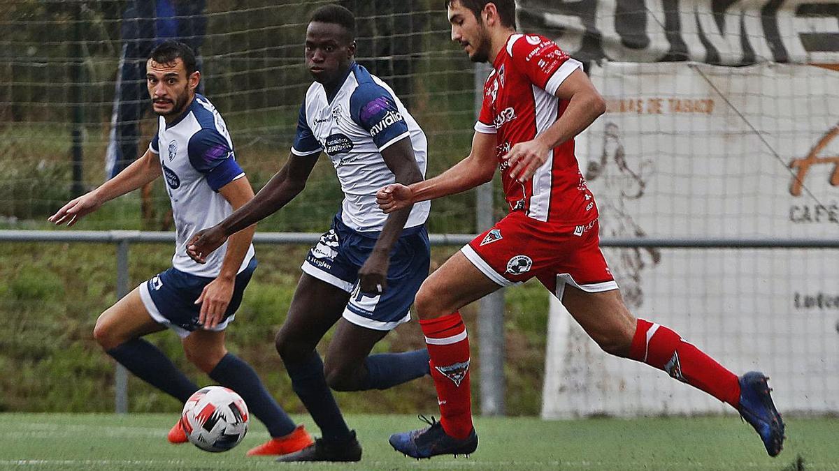 Un jugador del Atios conduce el balón ante la presión de dos rivales. |  // RICARDO GROBAS