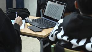 Un ordinador i un mòbil sobre un pupitre en una aula d’un institut de l’àrea metropolitana de Barcelona fa dos cursos, abans de la prohibició. | JORDI COTRINA