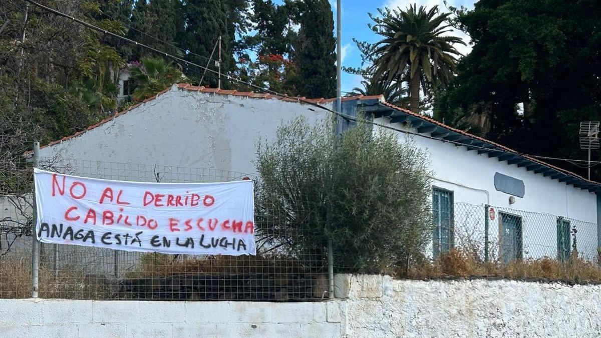 Una pancarta colocada sobre la fachada de la Casa del Caminero recuerda las demandas vecinales.