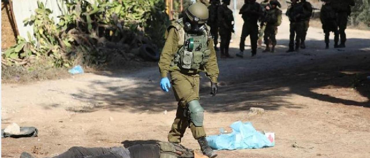 Un soldado israelí observa el cuerpo de un militante de Hamás abatido en e kibutz de Kfar Aza.