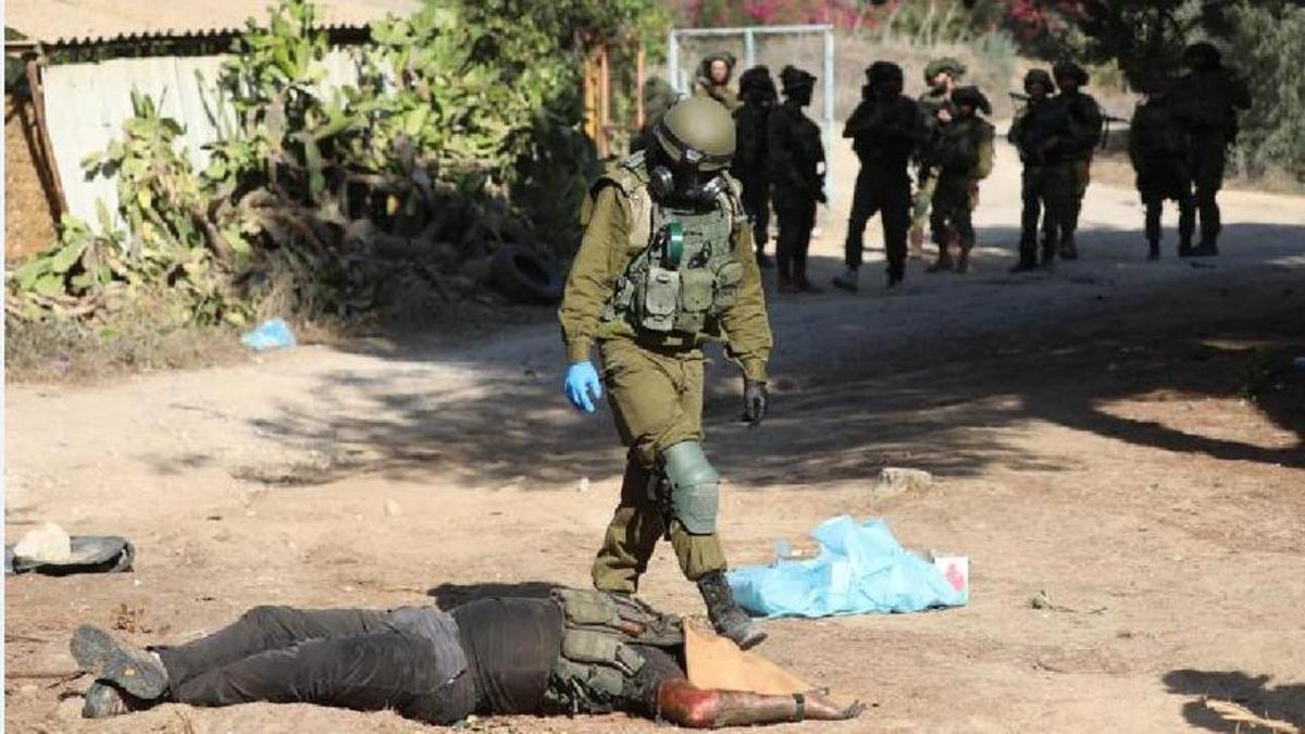 Un soldado israelí observa el cuerpo de un militante de Hamás abatido en e kibutz de Kfar Aza.