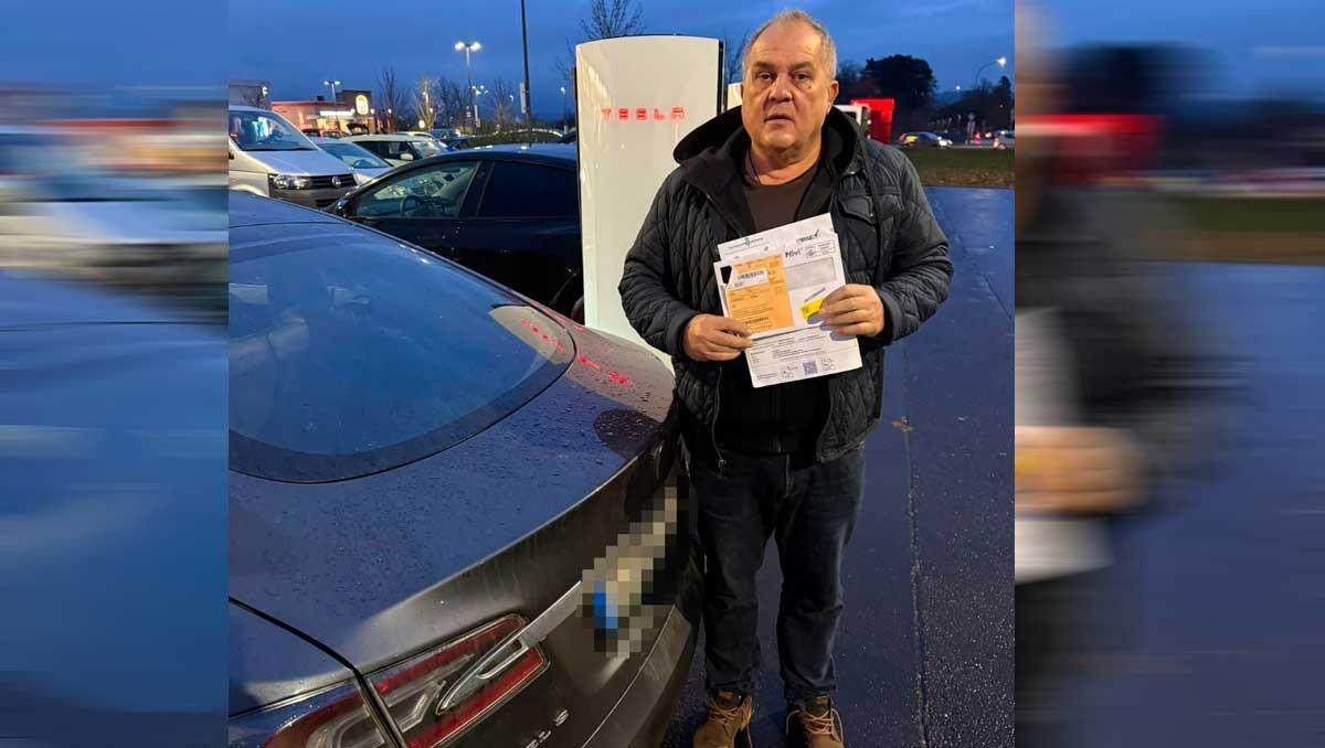 Joachim Fischer posa junto a su Tesla con la multa notificada por Cort.