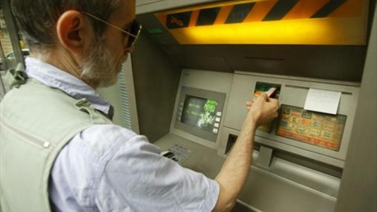 Una persona opera con una tarjeta en un cajero automático.