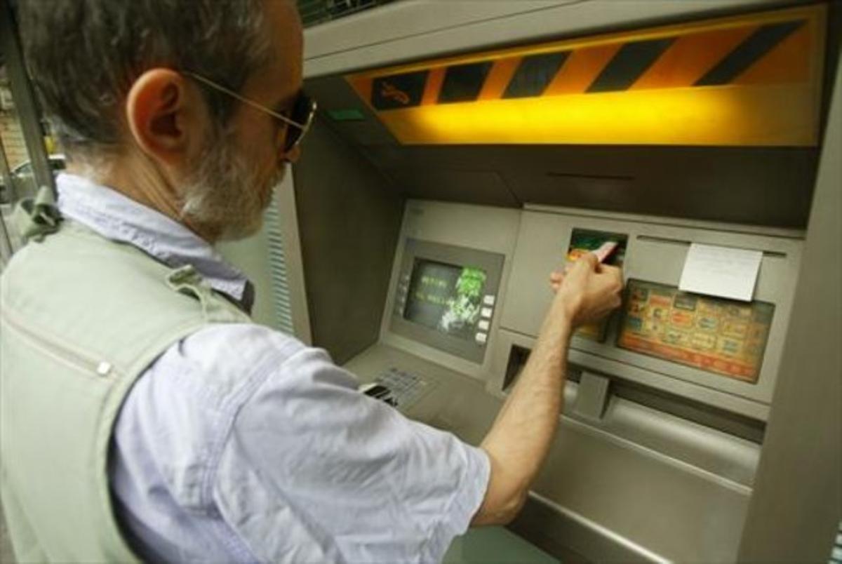 Una persona opera amb una targeta en un caixer automàtic. Una persona opera amb una targeta en un caixer automàtic.