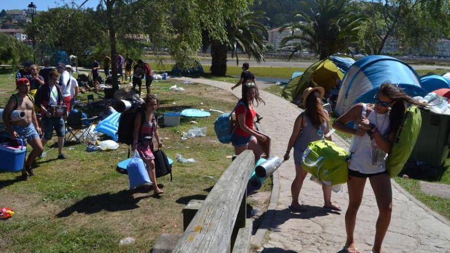 Campistas retirándose ayer por la mañana de la acampada del prau San Juan. A la derecha, el casco histórico riosellano con la normalidad de un domingo al mediodía en las terrazas.