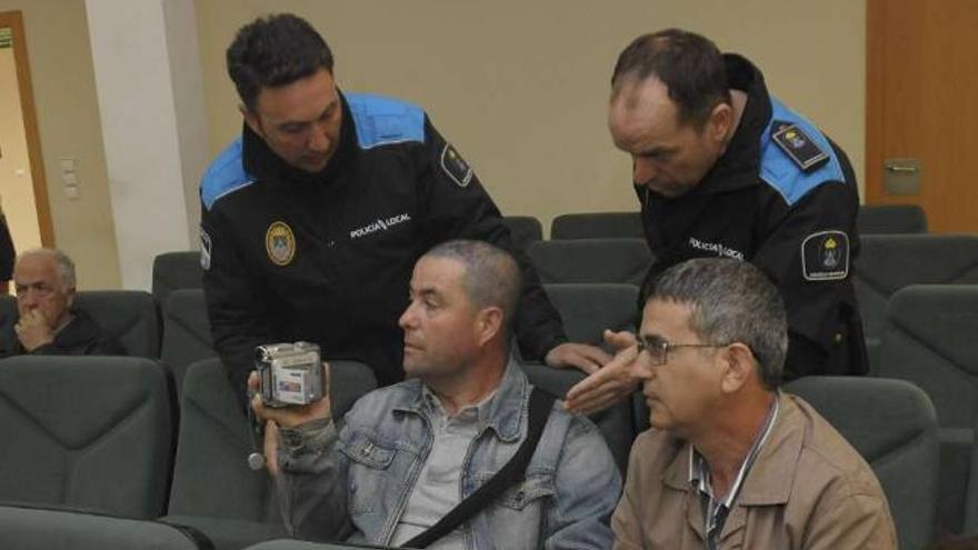 Los dos vecinos graban el pleno, ayer, mientras los policías les ordenan parar de filmar. / 13fotos