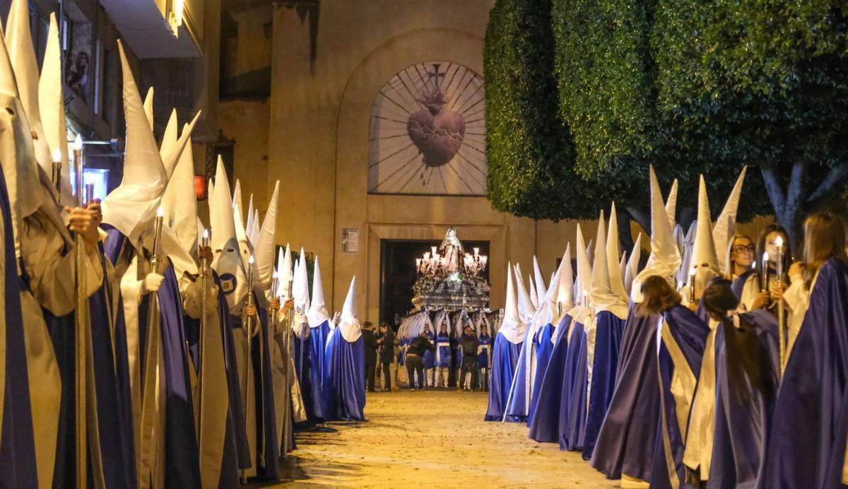 Las costaleras alzando a la Santa Mujer Verónica, con los nazarenos en primer término. | ÁXEL ÁLVAREZ