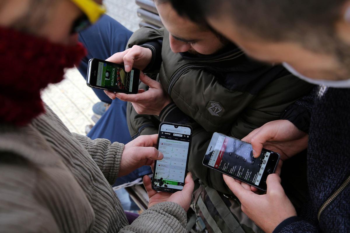 Jóvenes juegan con sus móviles en páginas de apuestas deportivas 'online'.
