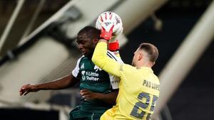 Pau López bloca un balón en el aire ante Tetteh en el Panathinaikos-Betis de octavos de Europa League en Atenas