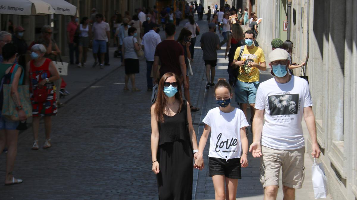 Pla mitjà d&#039;una família caminant tots amb mascareta aquest dissabte 26 de juny de 2021 a Girona. (Horitzontal)