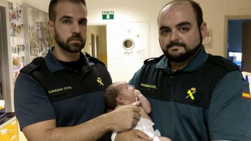 Los dos agentes del Instituto Armado, con el recién nacido que salvaron.
