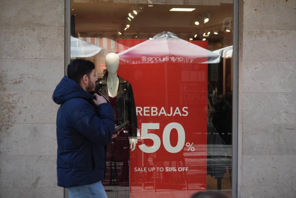 Un joven pasa por delante de una tienda con rebajas.