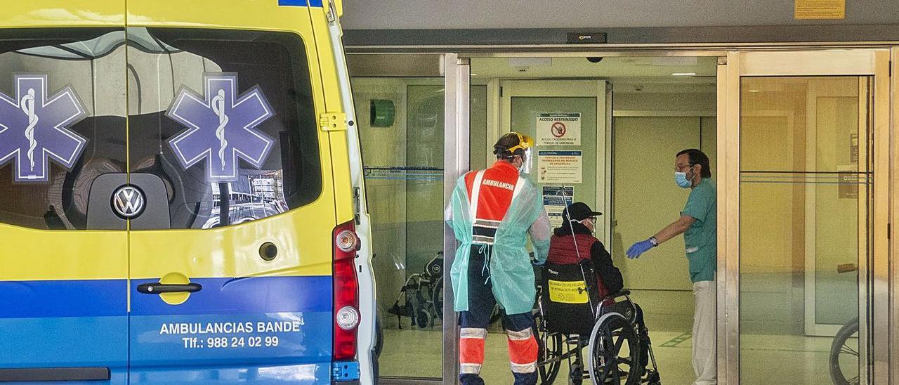 Un profesional sanitario entra con un hombre por la puerta de las Urgencias del CHUO.   | // IÑAKI OSORIO