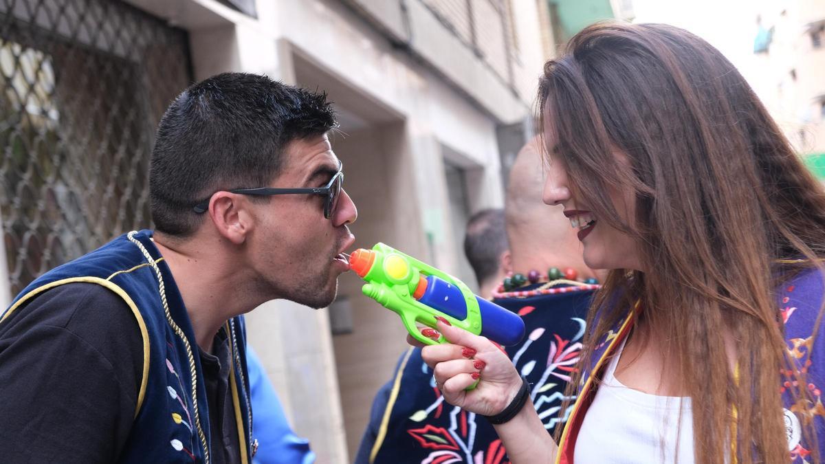 Una joven da alcohol a otro por medio de una pistola de agua en las Fiestas de Moros y Cristianos de Elda.