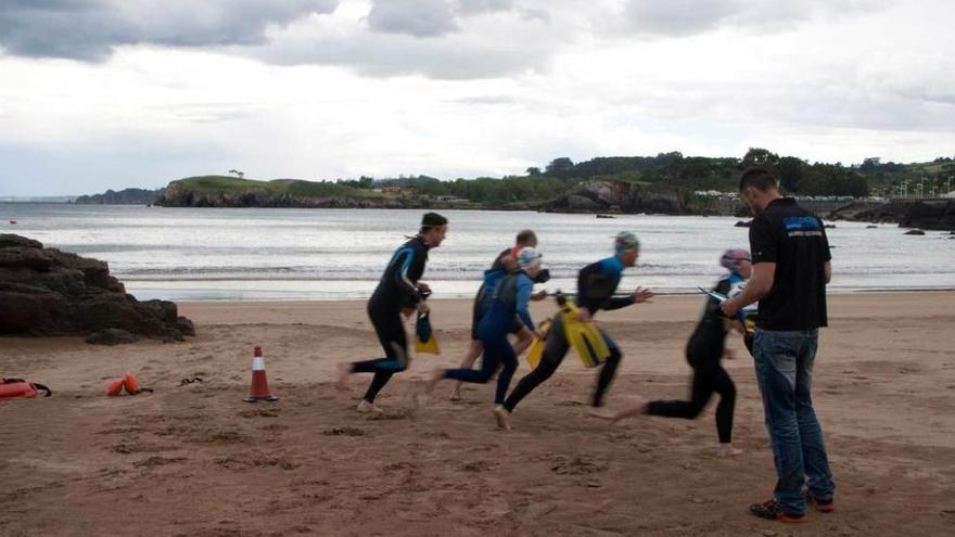 Un grupo de aspirantes a socorristas realiza la primera prueba física en la playa de Palmera ante la mirada del coordinador, Javier Reguera.