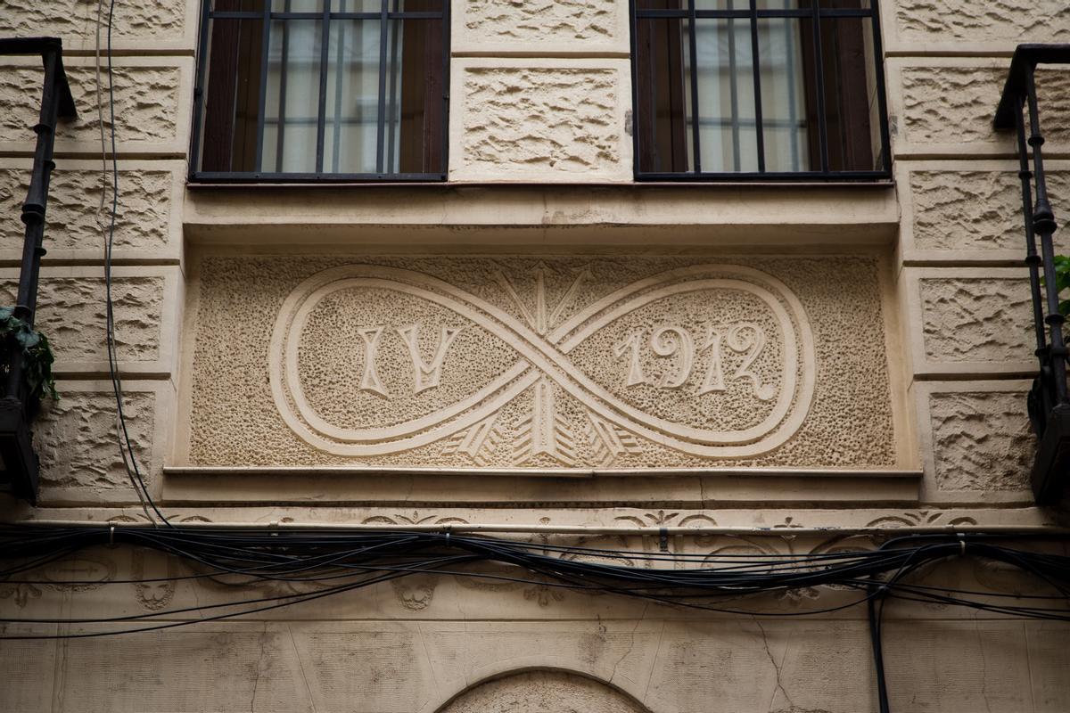 Infinito con flechas y la inscripción IV/1912 en la 'casa genital' de la calle de Montserrat, 12, en Madrid.