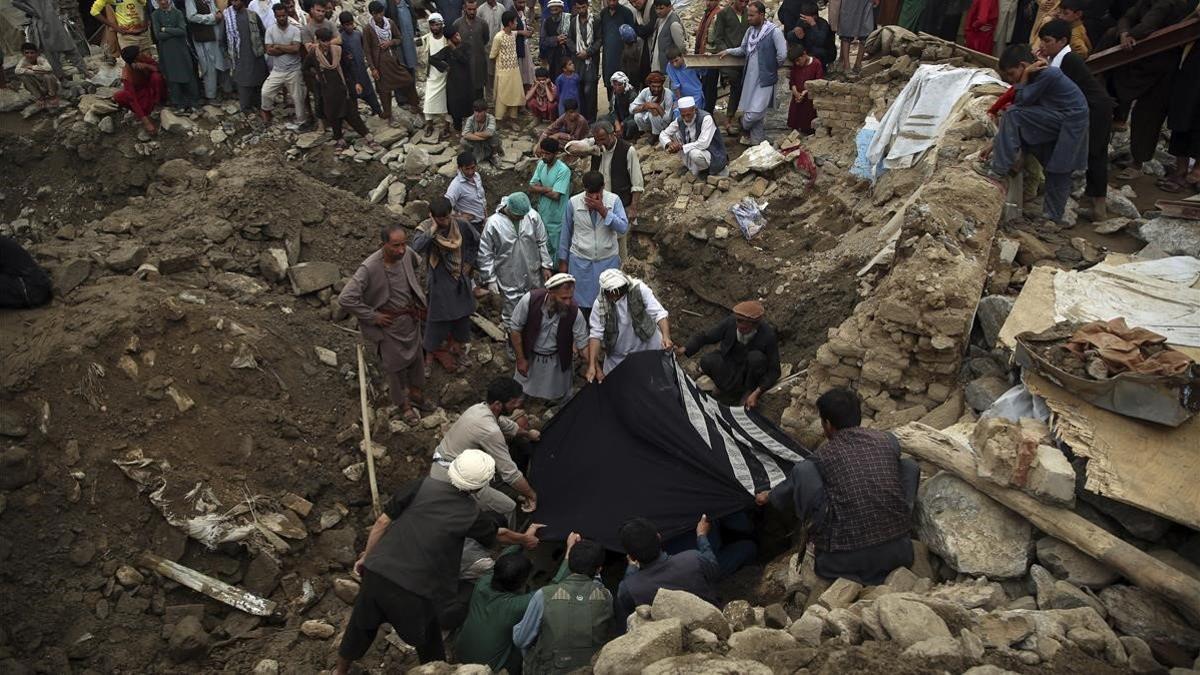 Un grupo de hombres localiza el cadáver de una mujer tras las inundaciones en la provincia de Parwan, este miércoles.
