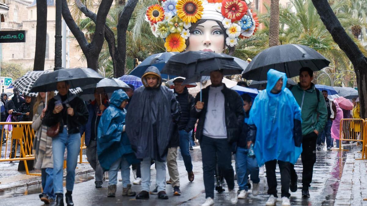 Un grupo de turistas pasea por València, bien pertrechados de paraguas y chubasqueros.