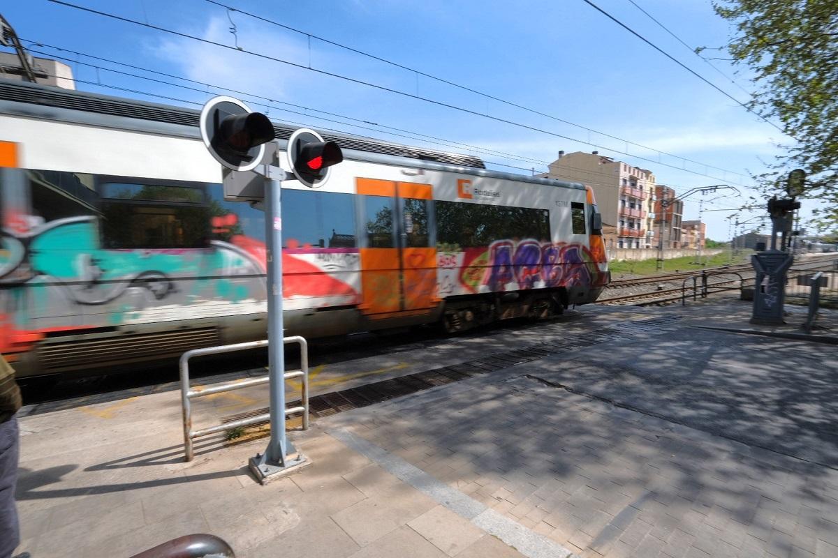 Un tren de rodalies transitant pel pas a nivell de l'avinguda Vilallonga de Figueres