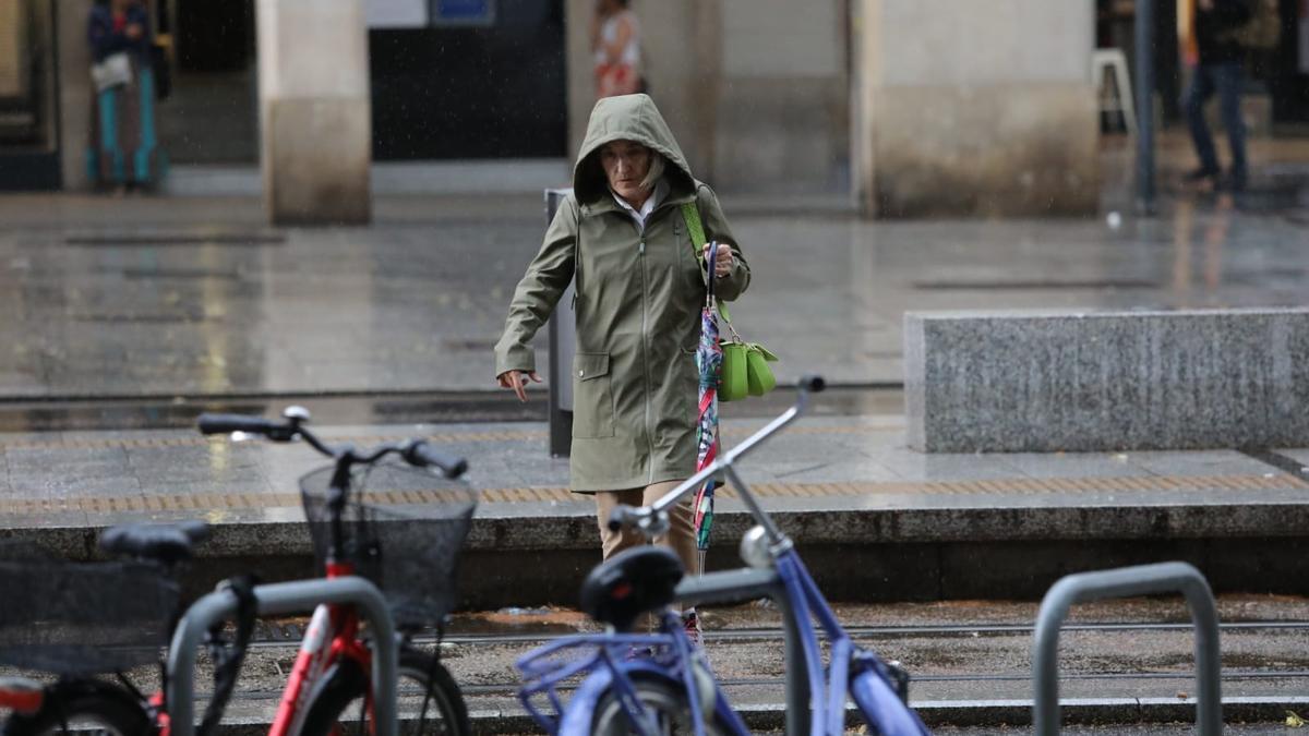 Una mujer se protege de la lluvia en Zaragoza con una capucha