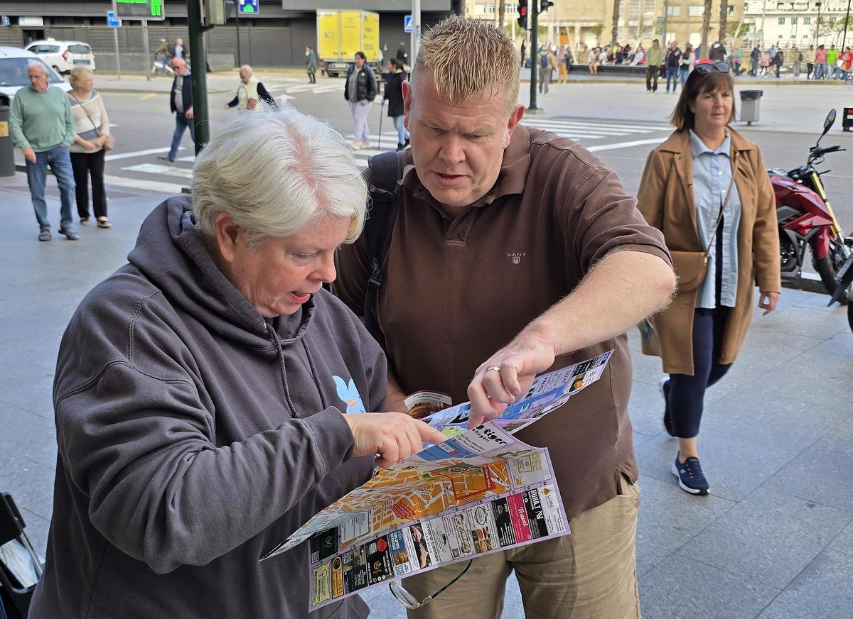 Dos turistas, con un mapa de la ciudad en la zona de A Laxe.