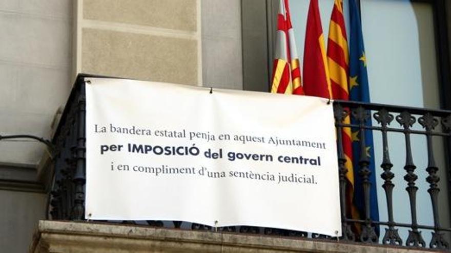 Detall del cartell on s&#039;expliquen els motius pels quals l&#039;Ajuntament d&#039;Igualada ha penjat la bandera espanyola i, a darrere, les quatre banderes: la d&#039;Igualada, l&#039;espanyola, la catalana i l&#039;europea.