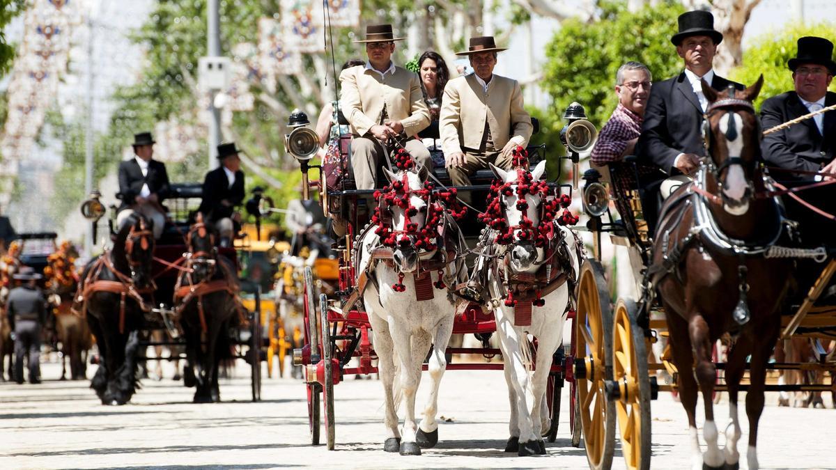 Varios coches de caballos pasean por el Real de la Feria de Abril de Sevilla