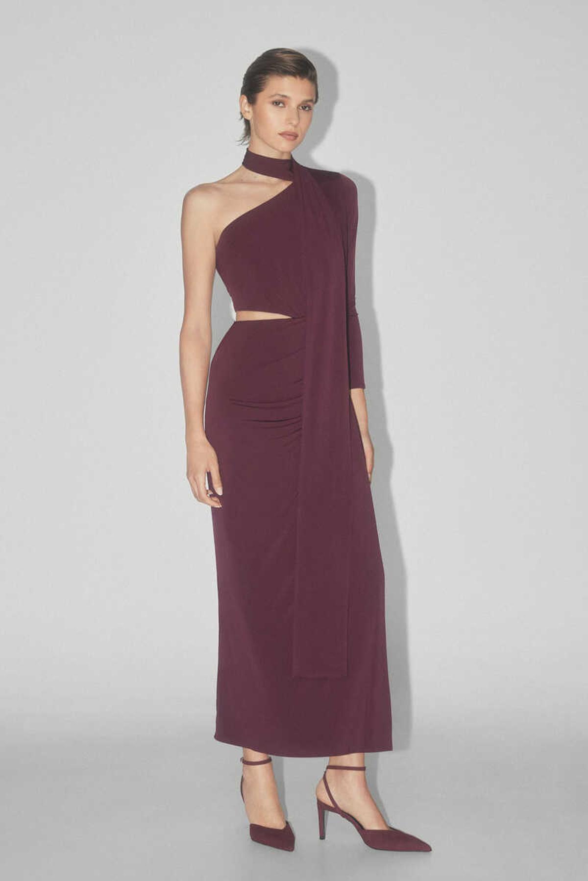 Vestido de punto de escote asimetrico con una manga, lazada que rodea escote y cuelga por espalda. Cut out en costado cintura y falda drapeada con abertura lateral.