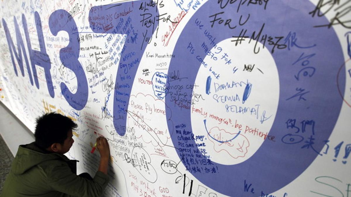 Un hombre escribiendo mensajes en honor a las víctimas del vuelo MH370 de Malaysia Airlines en el aeropuerto internacional de Kuala Lumpur (Malasia).