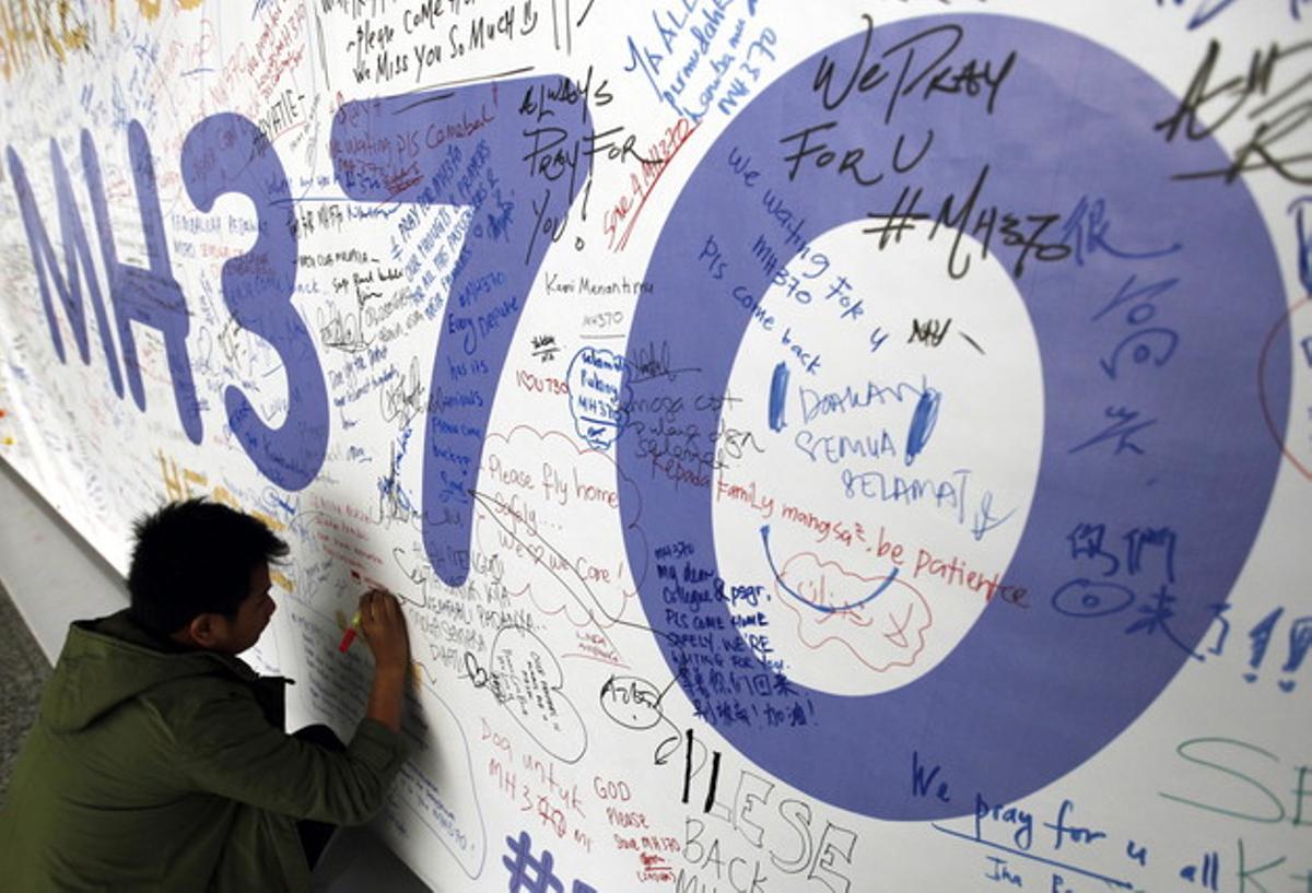 AUS01. KUALA LUMPUR (MALASIA), 30/07/2015.- Fotografía de archivo del 13 de marzo de 2014 de un hombre escribiendo mensajes en honor a las víctimas del vuelo MH370 de Malaysia Airlines en el aeropuerto internacional de Kuala Lumpur (Malasia). La aerolínea malasia Malaysia Airlines afirmó hoy que es demasiado pronto para confirmar que el fragmento de avión encontrado en una isla del océano Índico pertenece al vuelo MH370 desaparecido hace más de un año. EFE/MAK REMISSA