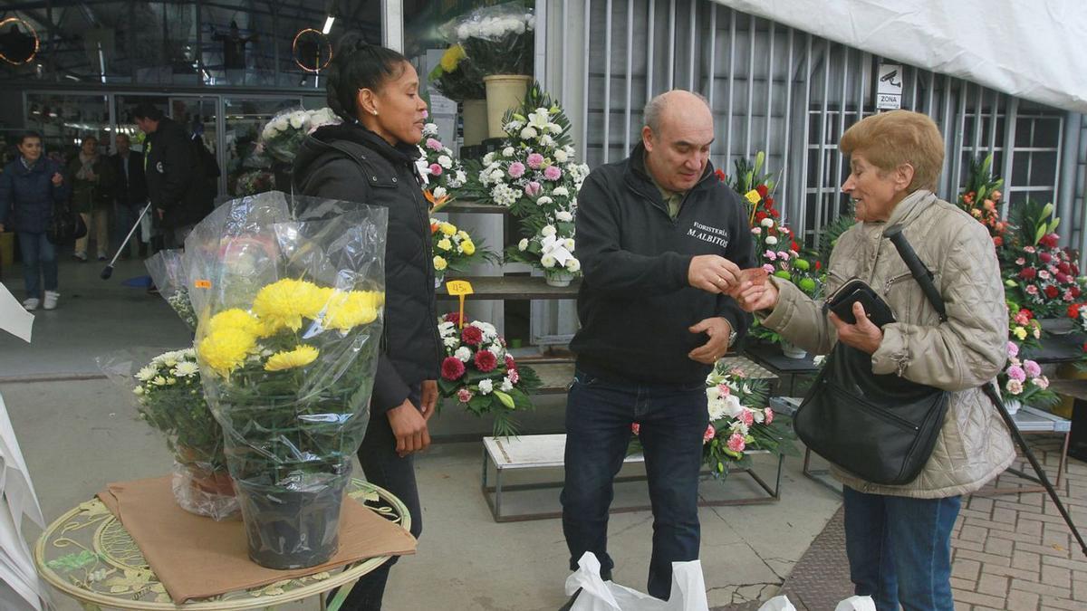 Varios clientes miran los centros de la floristería Albitos, en la Plaza de Abastos.