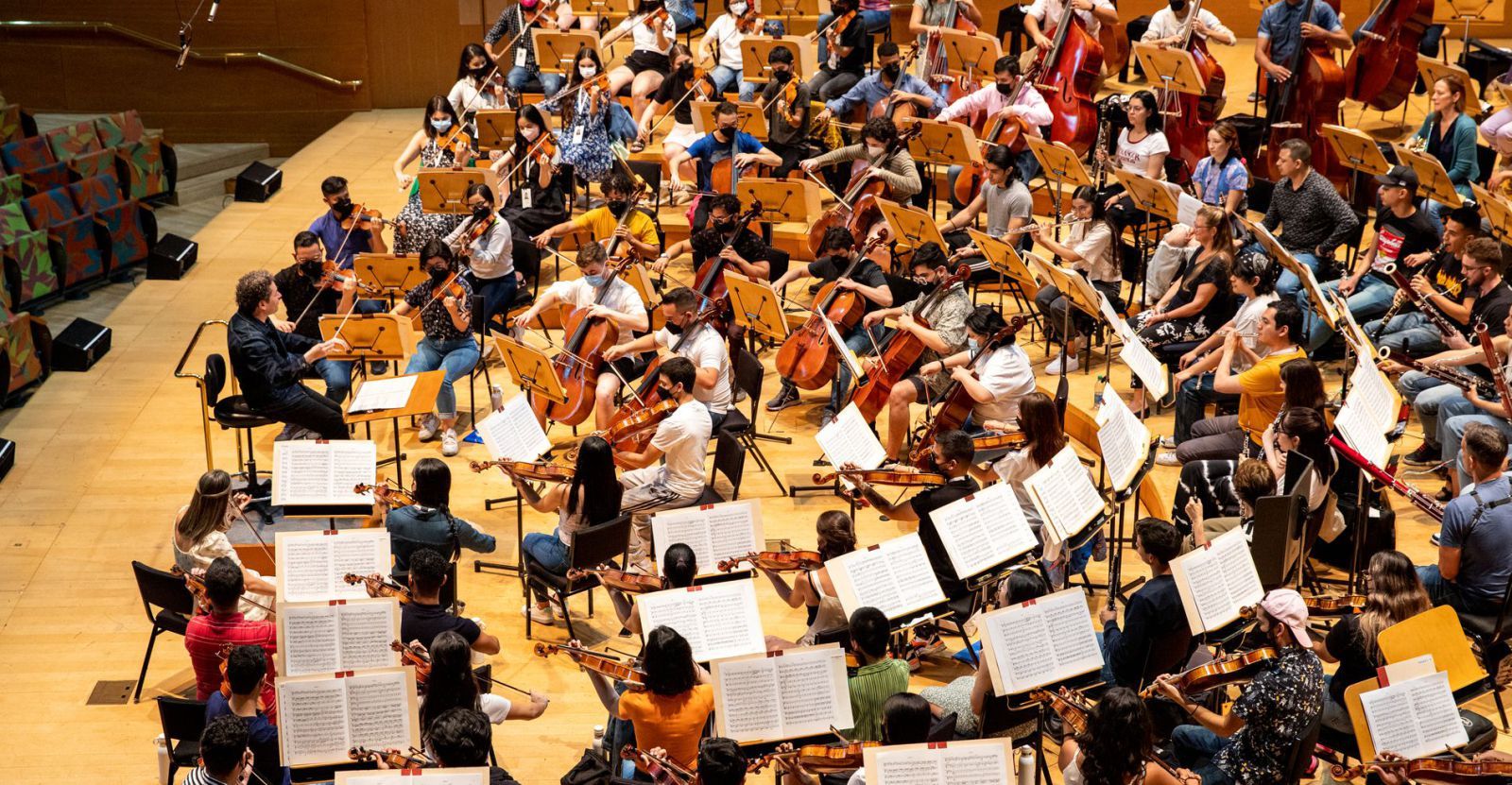 Gustavo Dudamel, dirigiendo a la Orquesta del Encuentro hace unas semanas en la ciudad californiana de Los Ángeles; entre los músicos, la violista asturiana Laura Torroba Bachiller. | María Romero