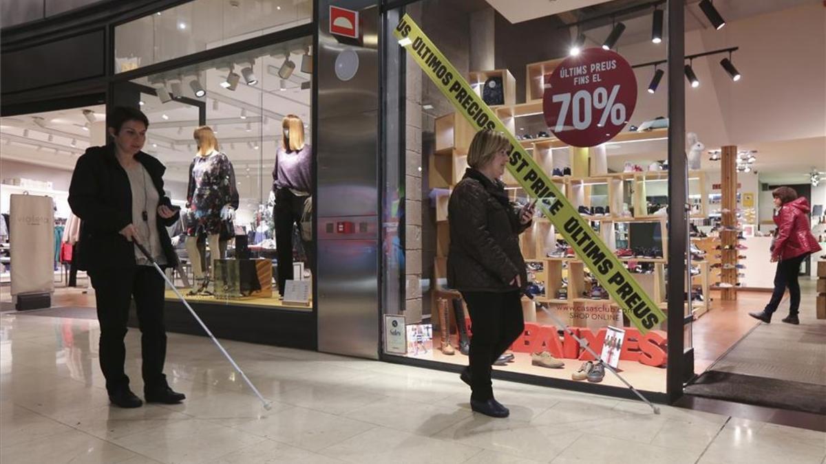 Dos discapacitados visuales pasean por el centro comercial Las Arenas de Barcelona, donde han instalado sensores que sirven para guiarles.