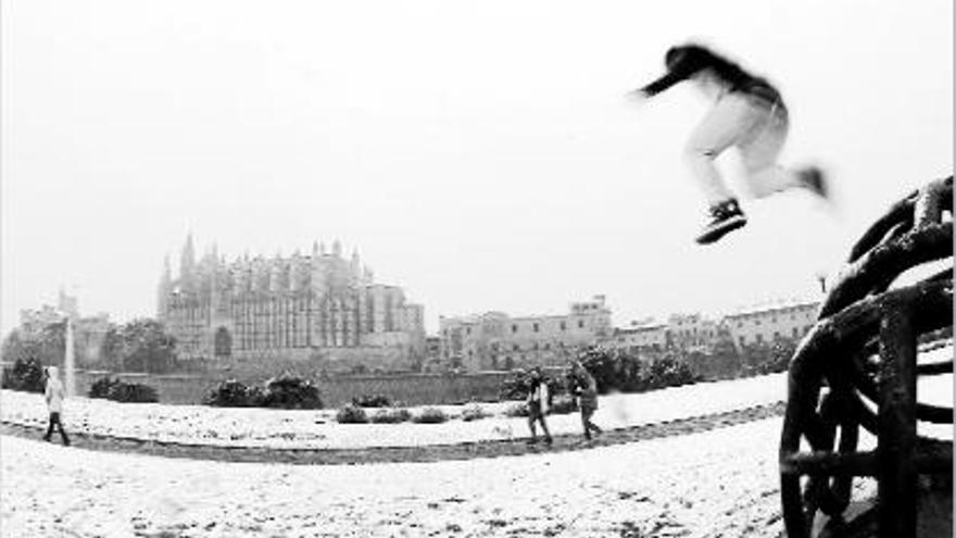 Un noi salta a la neu, davant d&#039;una imatge inusual de la catedral de Palma de Mallorca.