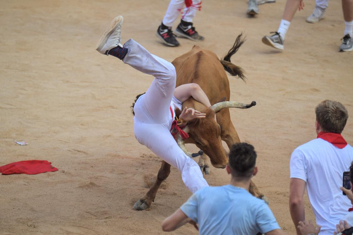 Un participante es derribado por una vaca joven después del encierro (corrida de toros) de las fiestas de San Fermín en Pamplona.