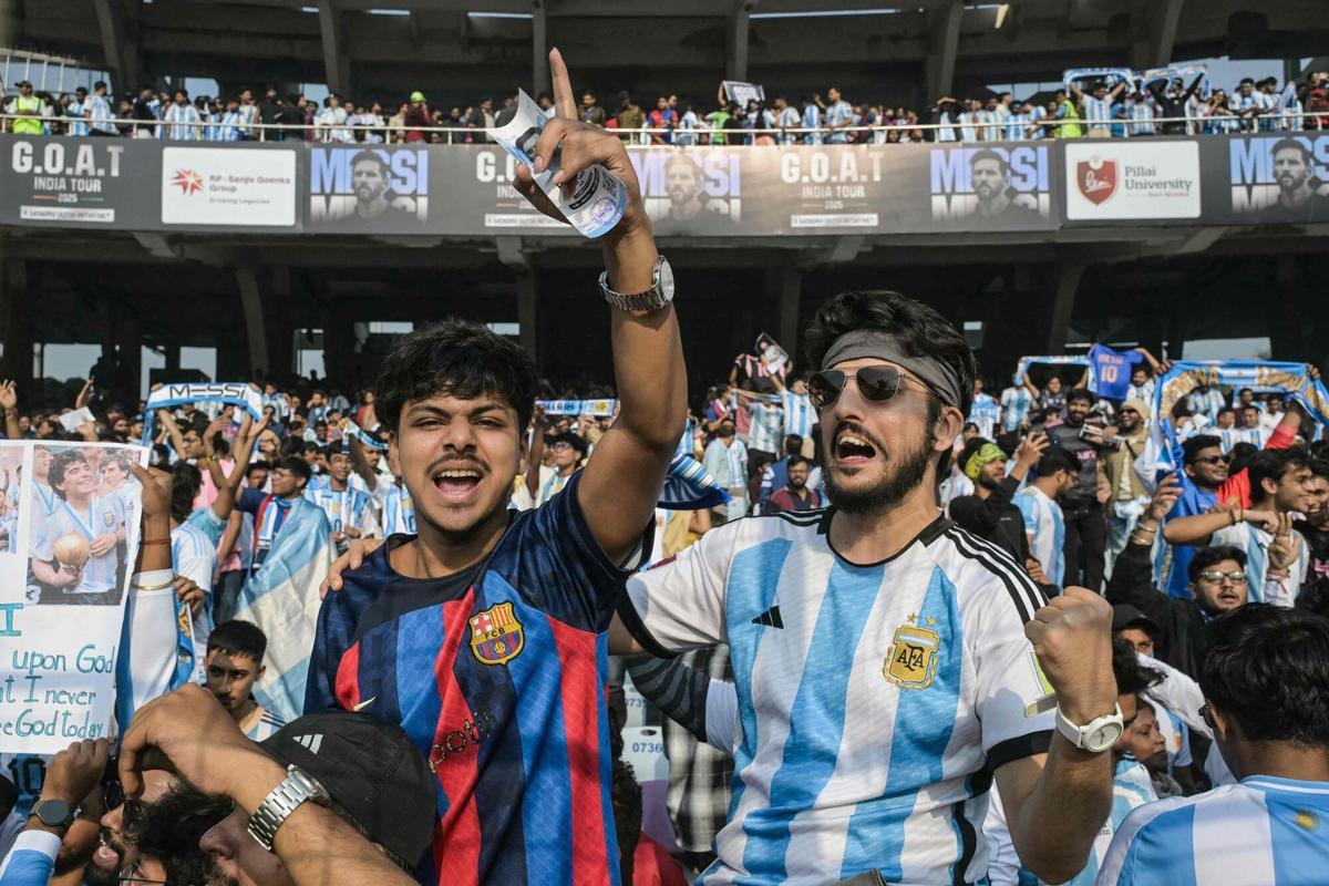 Fans of Argentinian football star Lionel Messi cheer from the stands before his arrival during the GOAT India Tour 2025 at the Salt Lake Stadium in Kolkata on December 13, 2025. Messi will unveil a 21-metre (70-foot) statue of himself in India on December 13, as he embarks on a three-day tour of the country that has sparked a fan frenzy. (Photo by Dibyangshu SARKAR / AFP)