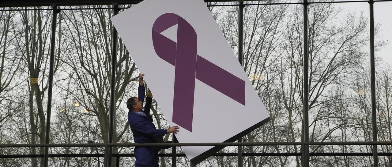 Un hombre sujeta un lazo morado, símbolo de la lucha contra la violencia machista.