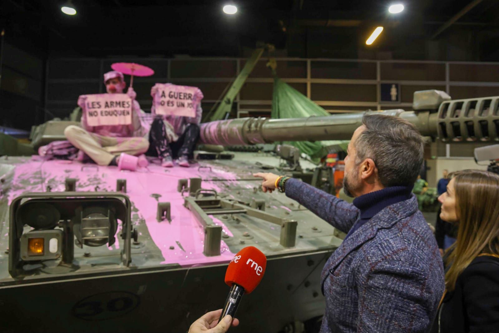 Unos pacifistas rocían pintura rosa sobre una tanqueta en Expojove: "Las armas no educan"