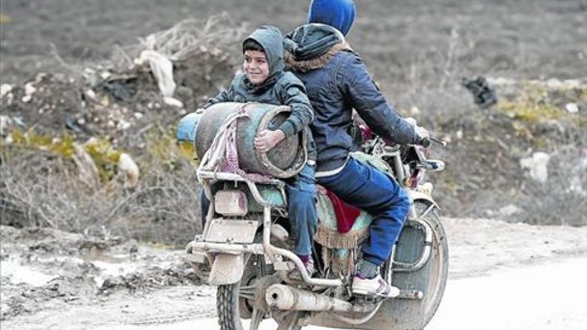 Un niño sirio refugiado carga un bidón de combustible en el valle de la Bekaa, en el Líbano.