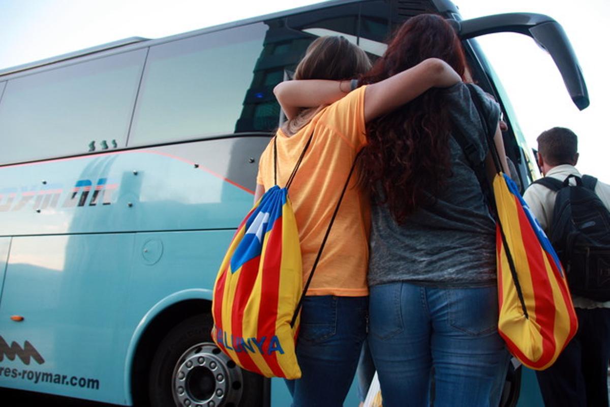 Dos jóvenes con ’estelades’ se disponen a subir a un autocar rumbo a Barcelona, esta mañana en Valencia.