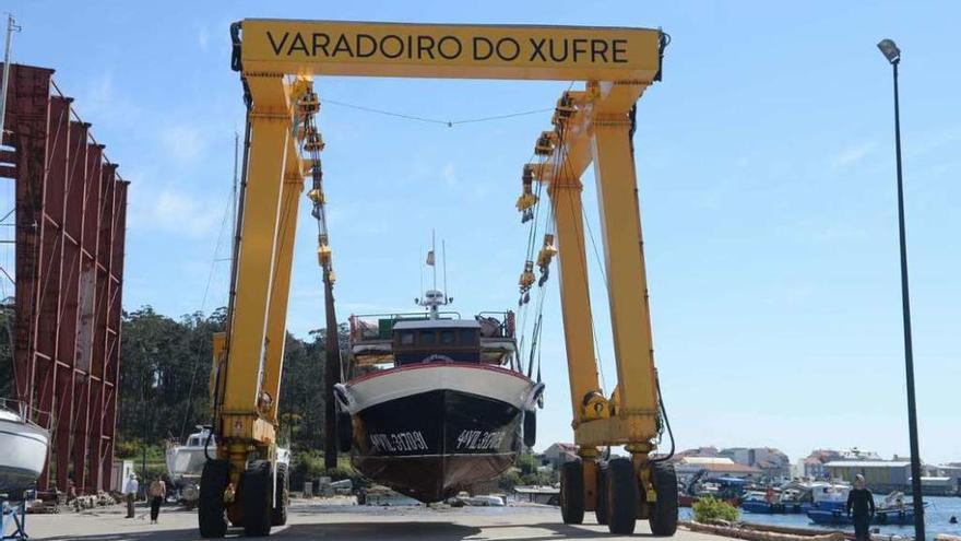 Un bateeiro es conducido a tierra con una grúa en A Illa para realizar trabajos de puesta a punto. / N.Parga