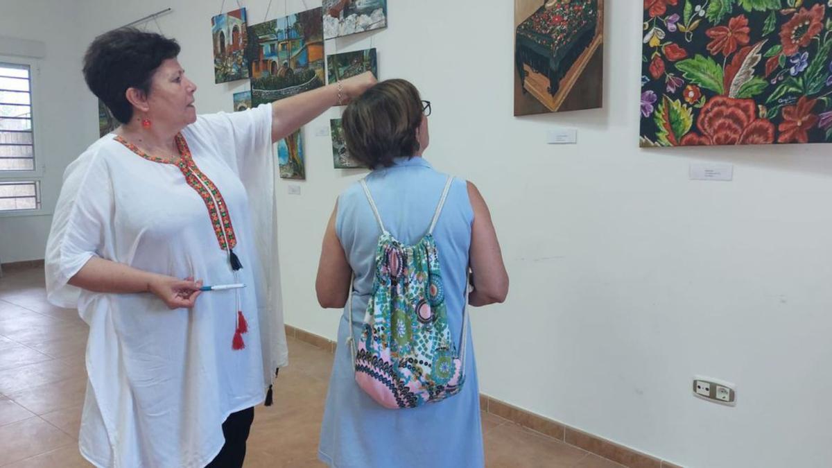 Angélica López, explicando una de sus obras a una visitante de la exposición.